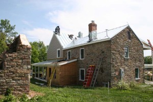 The bulk of the roofing has been installed.  The chimneys are temporarily wrapped since the flashings are not complete.  The lower enclosed portion of the side porch is the location of a unique 'cricket' that is especially made to accomodate this lower window.