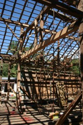 With the roof removed, the skip sheathing casts shadows across repair and original timbers.