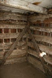 Removing the interior finishes shows that this building was constructed in a very distinctive style where the logs are tenoned into vertical corner posts.