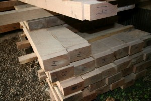 Stacks of floor joists with square-ruled ends waiting to drop into their bearing pockets.